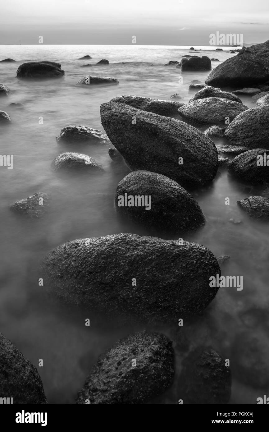 Litorale roccioso nel tramonto in bianco e nero, con esposizione lunga Foto Stock