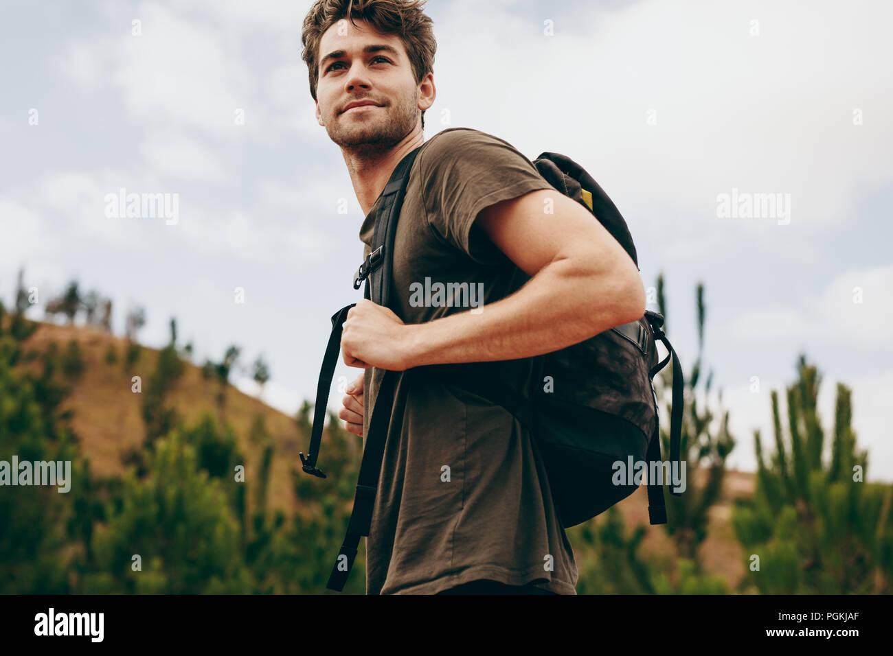 L'uomo escursionismo in una località di campagna. Vista laterale di un uomo che indossa un sacchetto a piedi attraverso una foresta. Foto Stock
