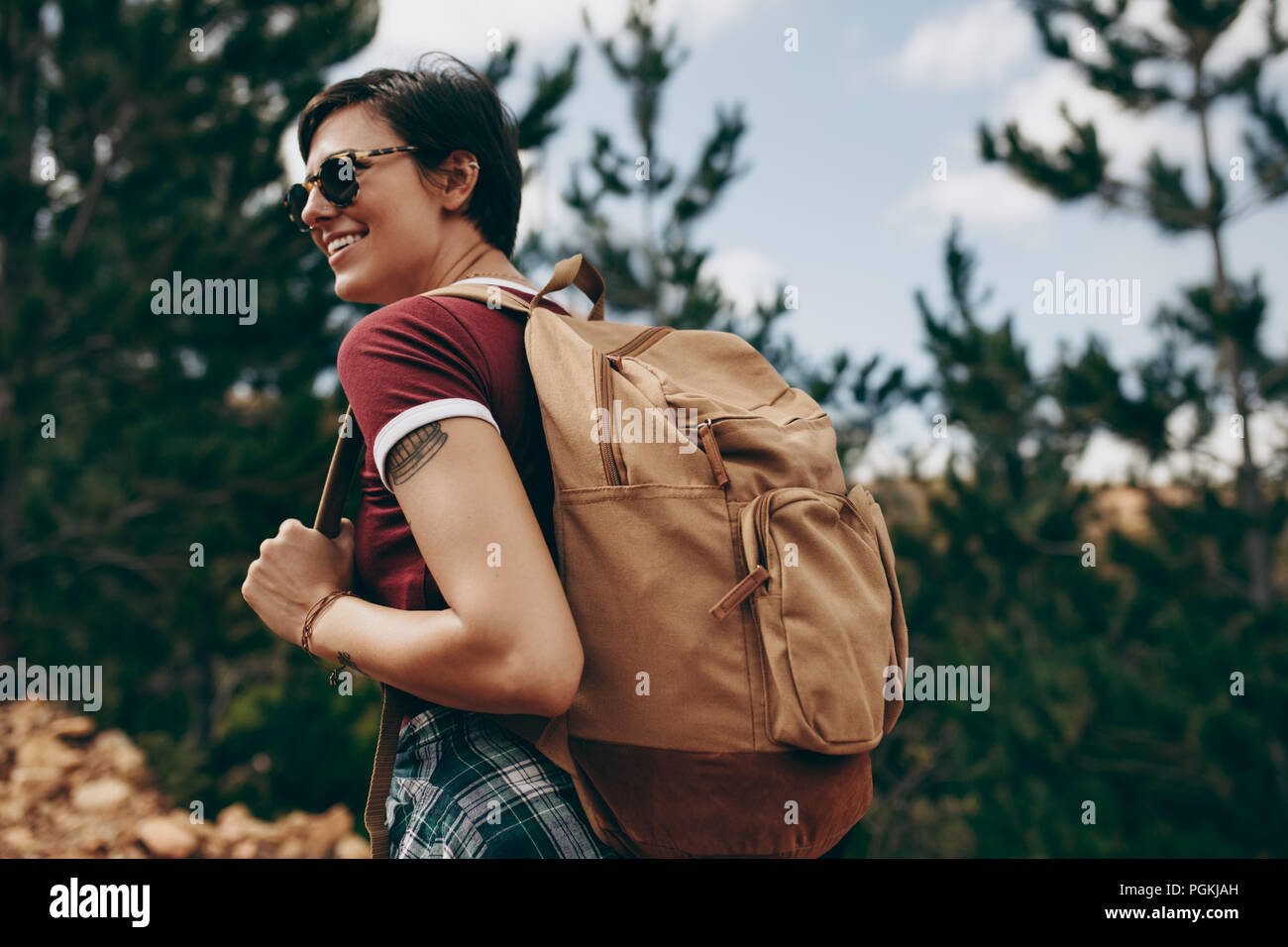 Explorer woman hiking in una località di campagna. Vista laterale di una donna che indossa uno zaino e occhiali a piedi attraverso una foresta. Foto Stock