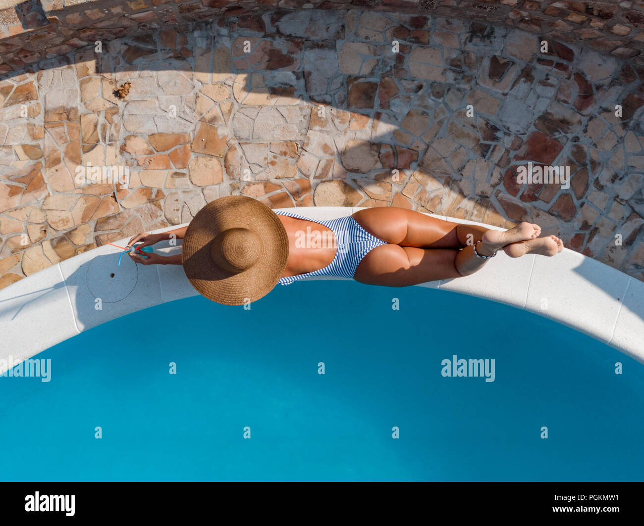Bella giovane donna godere dalla piscina. Ella è sdraiato a prendere il  sole, aveva coperto con un enorme cappello di paglia, vicino mare azzurro  Foto stock - Alamy