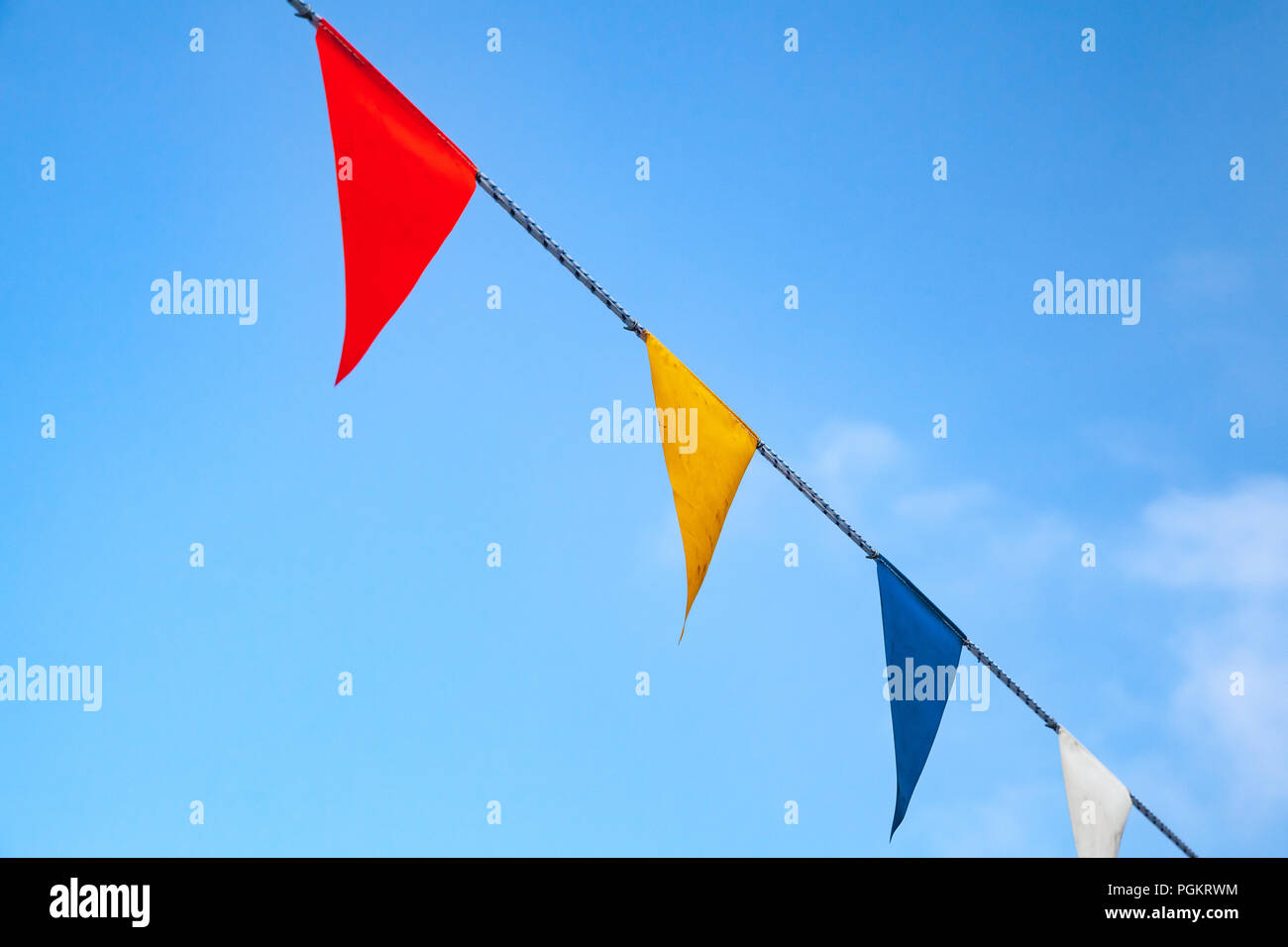 Triangolo colorati Bandiere sulla corda blu su sfondo con cielo nuvoloso Foto Stock