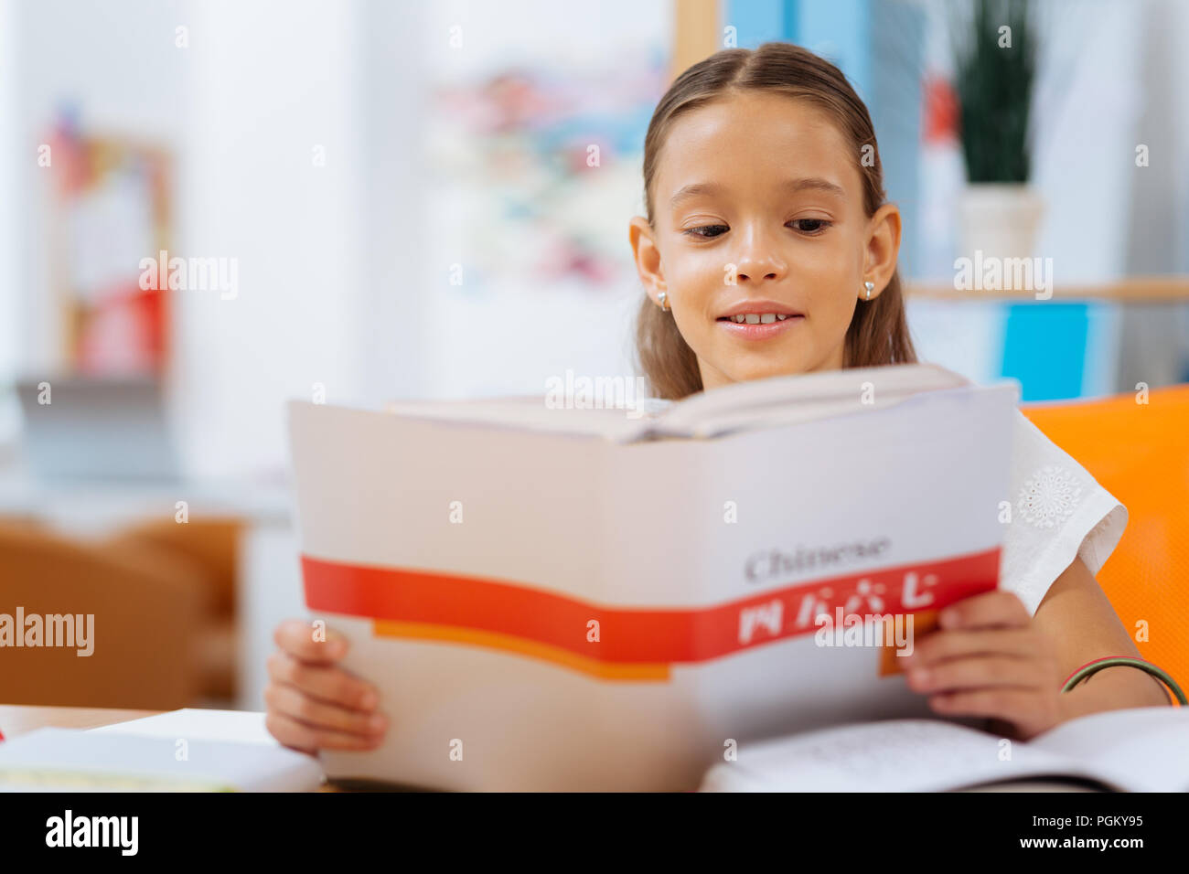 Grave schoolgirl la lettura di un libro molto attentamente Foto Stock