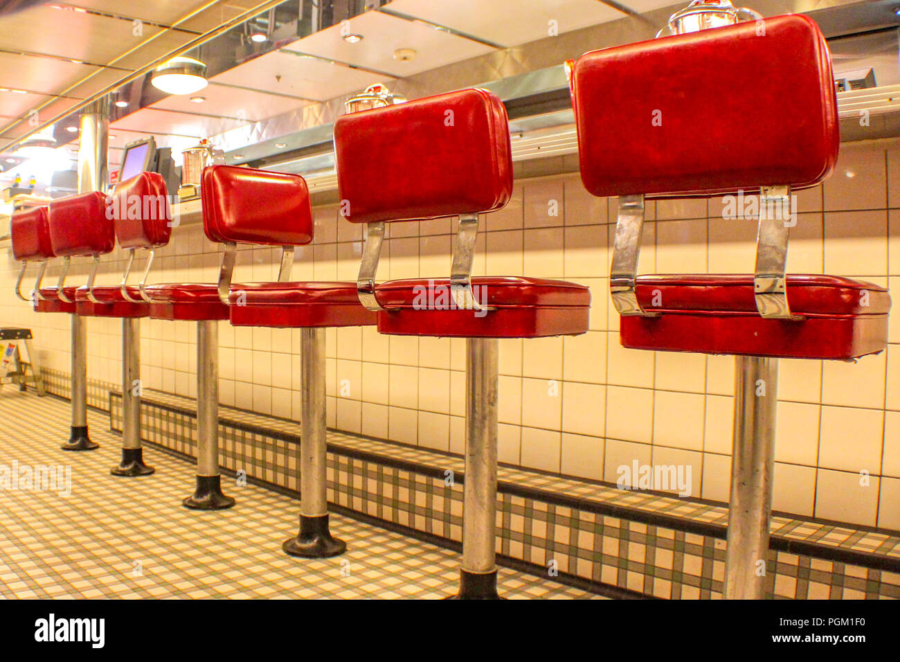 Veiw cercando lungo una fila di sgabelli rosso in American Diner Foto Stock