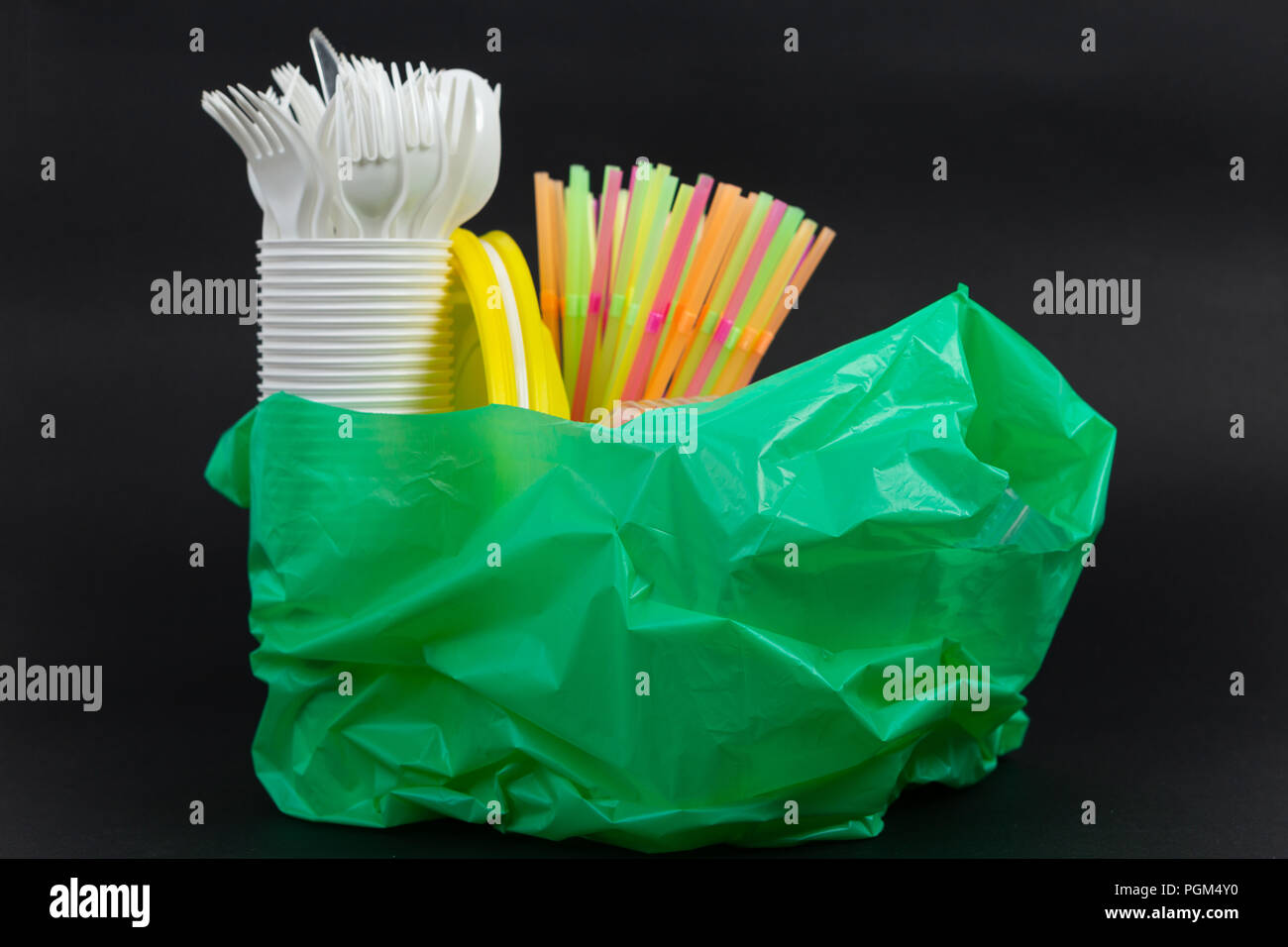 Il verde il sacchetto di plastica con uso singola cannucce piatti tazze e  posate di rifiuti come rifiuti riciclare inquinamento ecologia indesiderata  concetto su sfondo nero Foto stock - Alamy