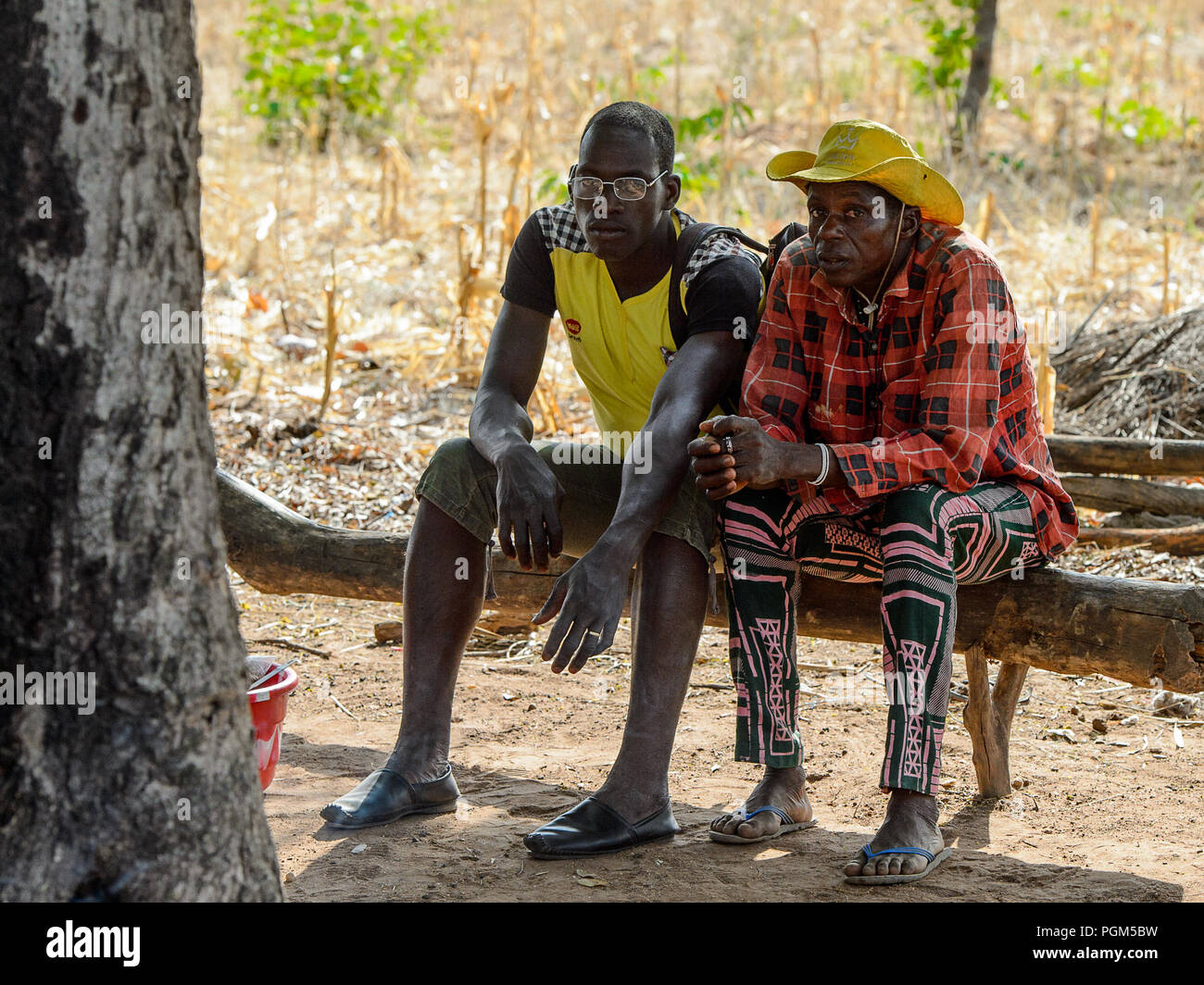 KOUTAMMAKOU, TOGO - Jan 13, 2017: Non identificato gli uomini Togolese sedersi sul montante in legno nel villaggio. Il Togo di persone soffrono di povertà a causa della cattiva eco Foto Stock