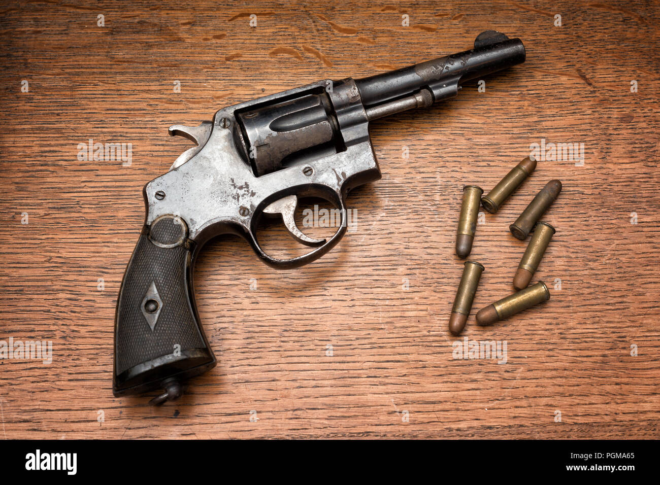 Vecchio polizia militare rusty revolver revolver e i suoi sei pallottole prevista su di un tavolo di legno Foto Stock