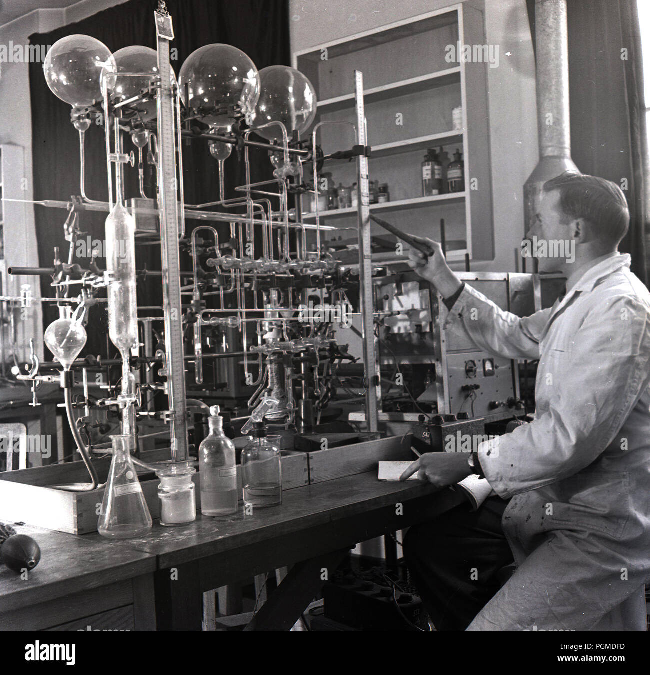 Degli anni Cinquanta, storico, maschio scienziato in camice bianco lavora in un laboratorio con numerose provette in vetro a oxford univ, per testare o investiage reazioni gassose, Oxford, Inghilterra, Regno Unito. Foto Stock