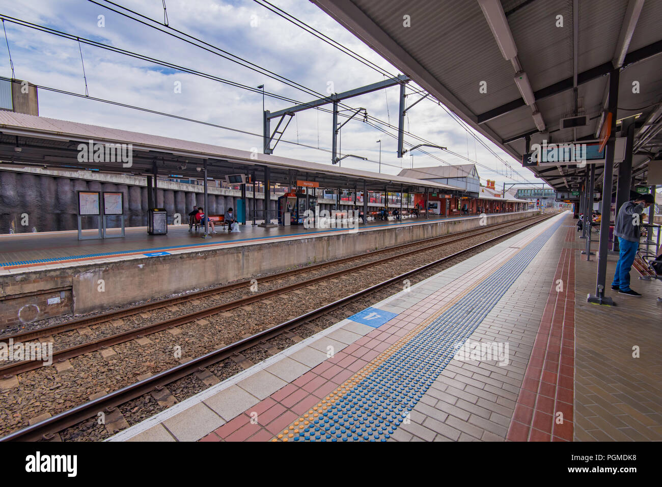 La gente in attesa a due del lungo rettilineo di piattaforme a Hornsby su Sydney North Shore Line, Australia Foto Stock