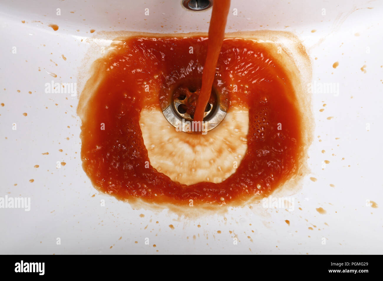 Close up sporco marrone ruggine acqua inquinata che scorre dal rubinetto nel lavandino del bagno, ad alto angolo di visione Foto Stock