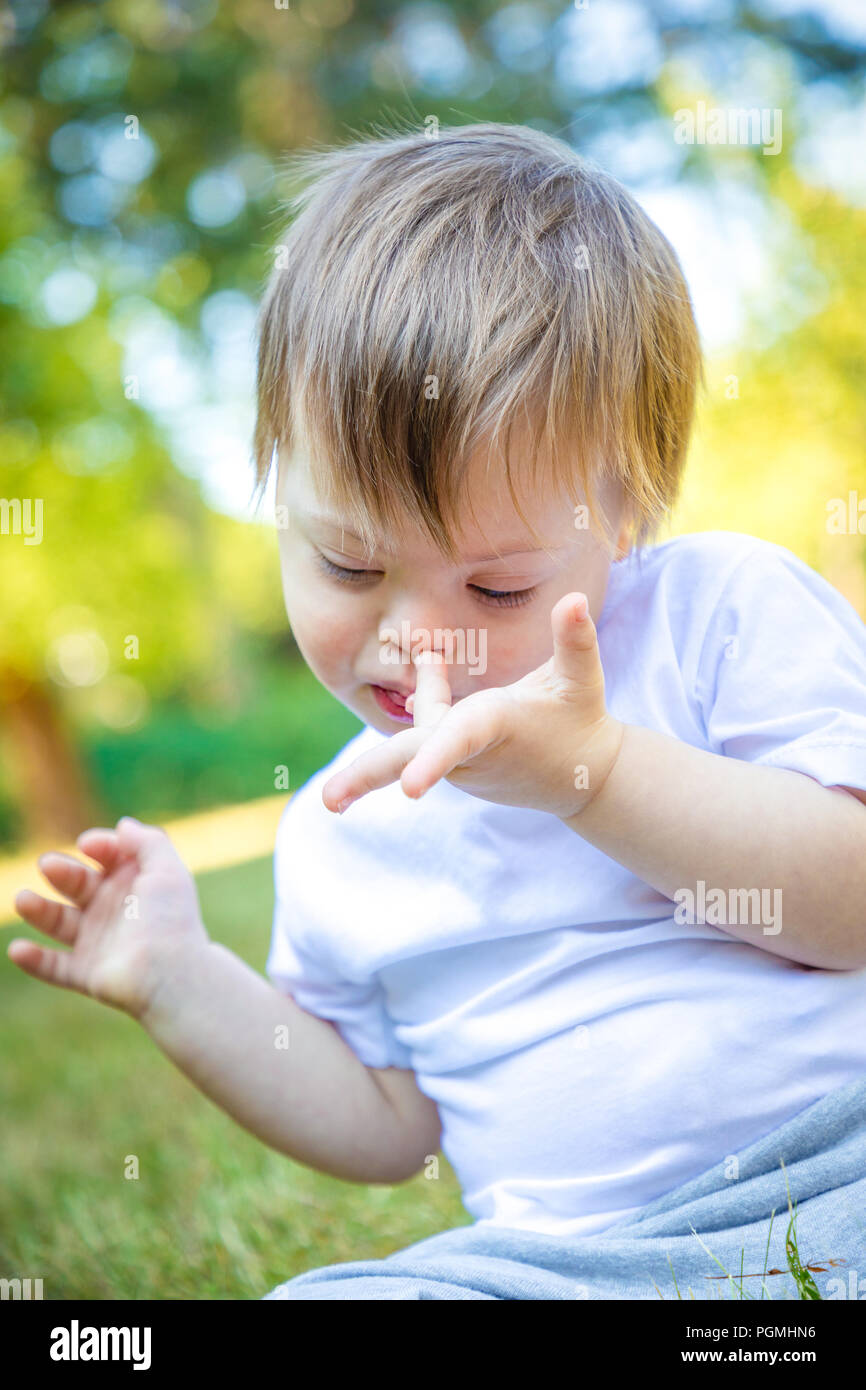 Ritratto di carino piccolo ragazzo con la sindrome di Down giocando in natura Foto Stock