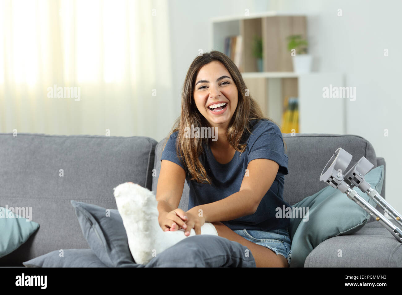 Donna disabile ridere guardando seduto su un divano nel salotto di casa Foto Stock