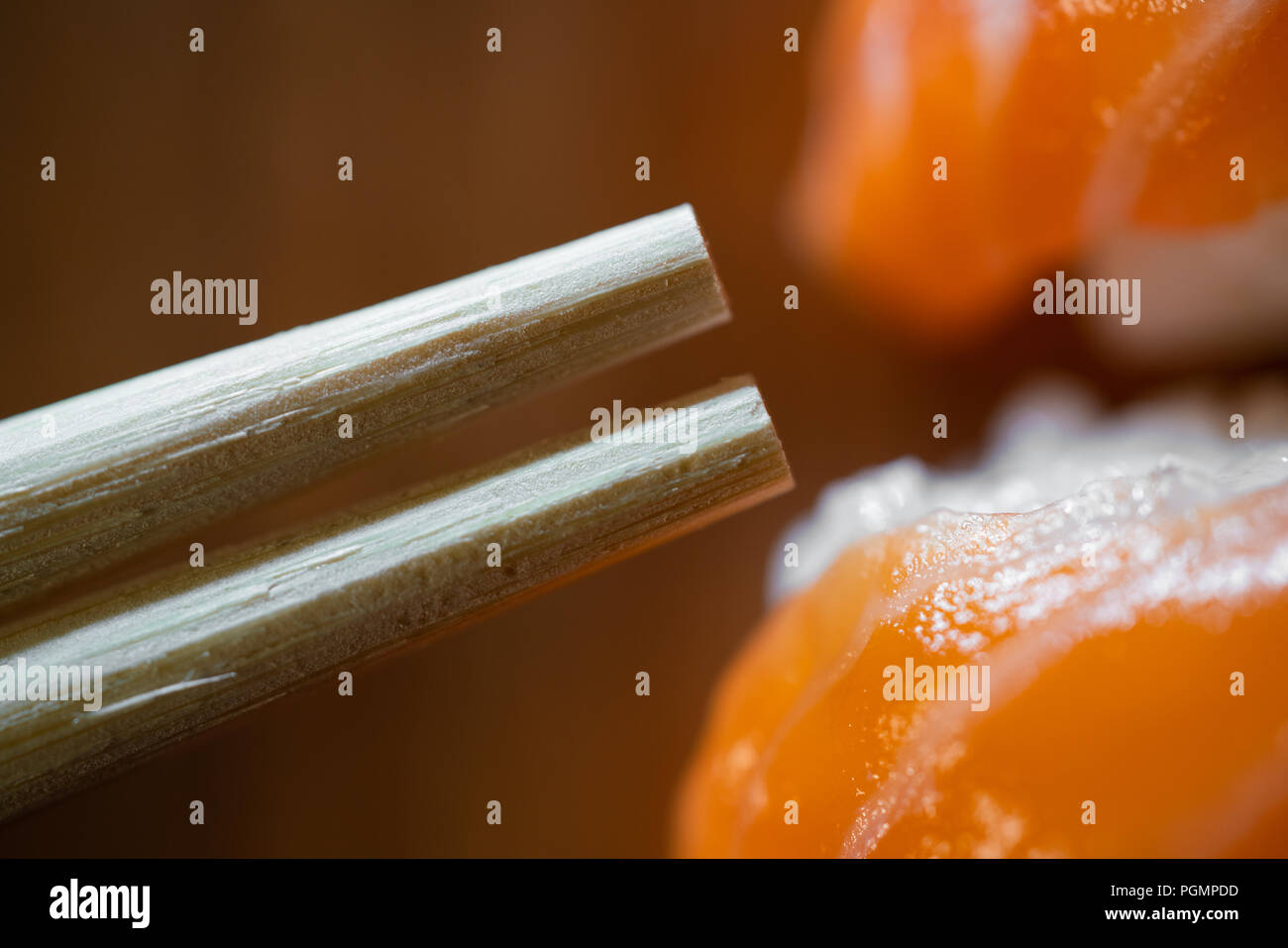 Usa e getta bacchette di bambù e salmone sushi di ripresa macro su sfondo di legno Foto Stock