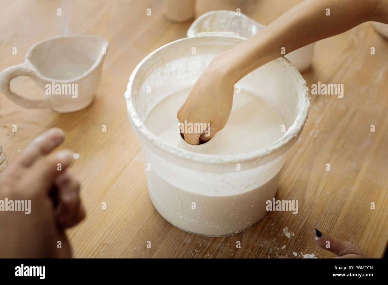 Potter femminile mettendo la sua mano in sostanza di argilla Foto Stock