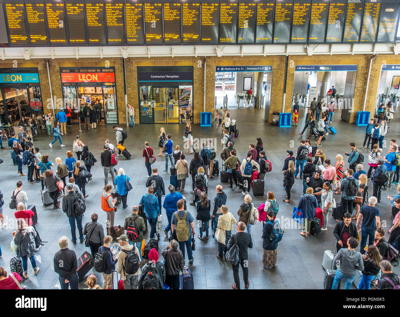 Passeggeri ferroviari,guardare,schede di partenza,la stazione di Kings Cross,Londra,Inghilterra Foto Stock