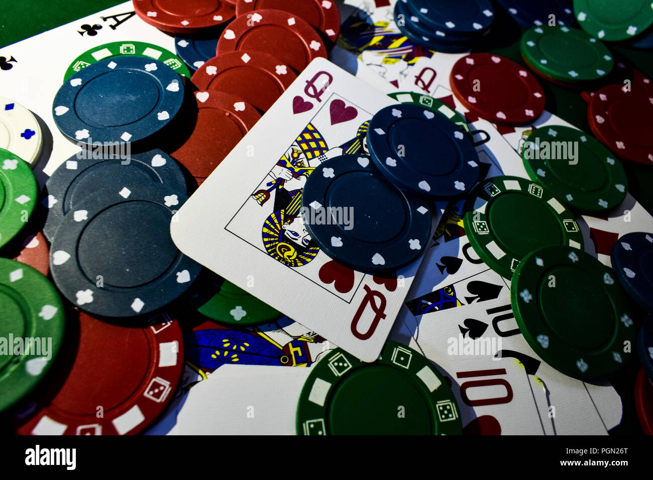 Regina di Cuori e di altre carte da gioco su un tavolo del poker piena di poker chips. Sfondo di poker. Foto Stock