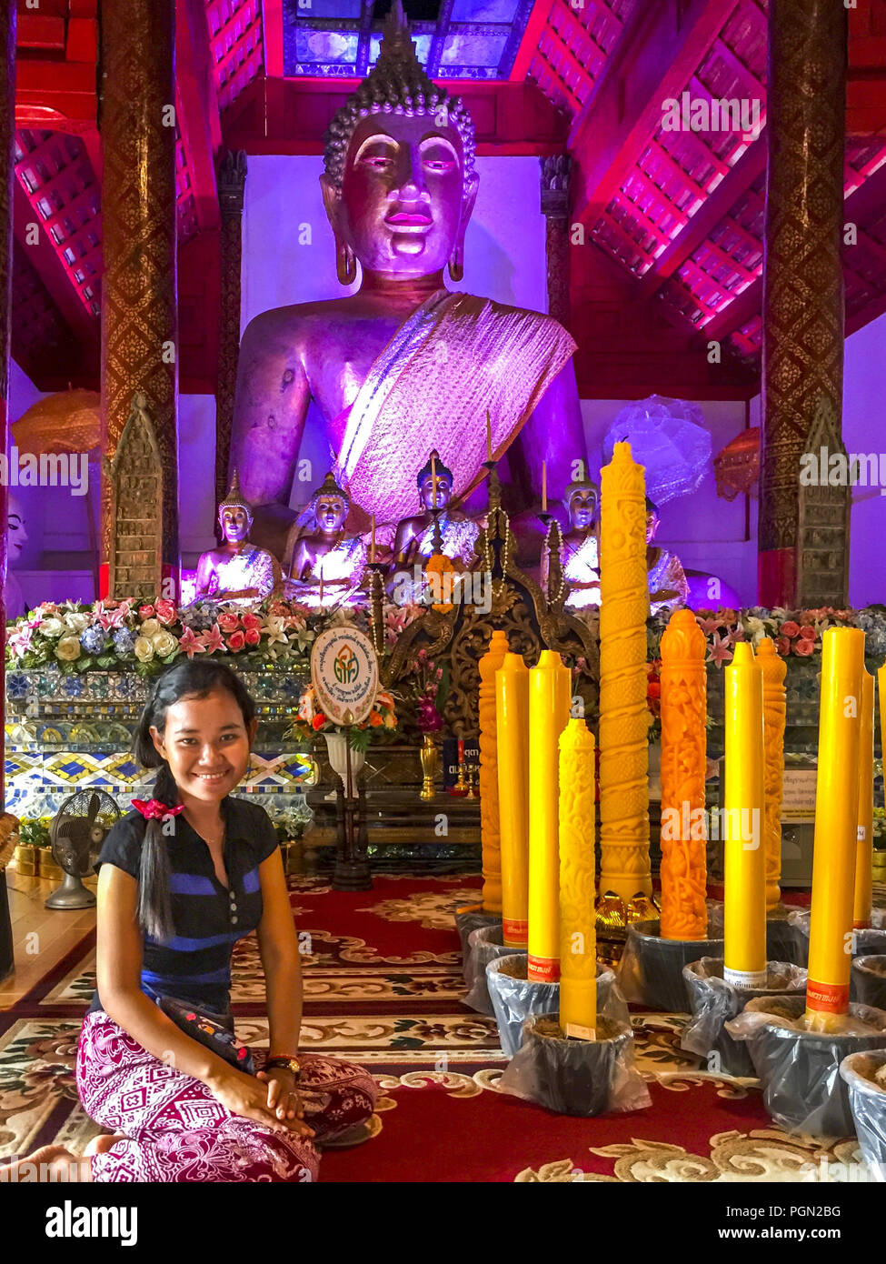 Ragazza asiatica di fronte molto grande Buddha colorata all'interno di wat phako tempio a Chiang Mai, Thailandia. Foto di rilascio: Sì Foto Stock