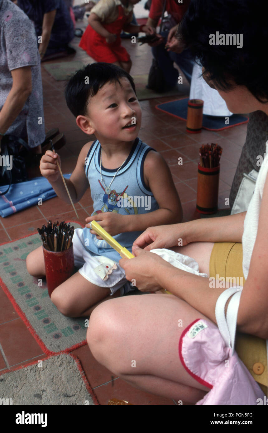 Madre e figlio al culto ancestrale tempio in Hong Kong preparano l'incenso Foto Stock