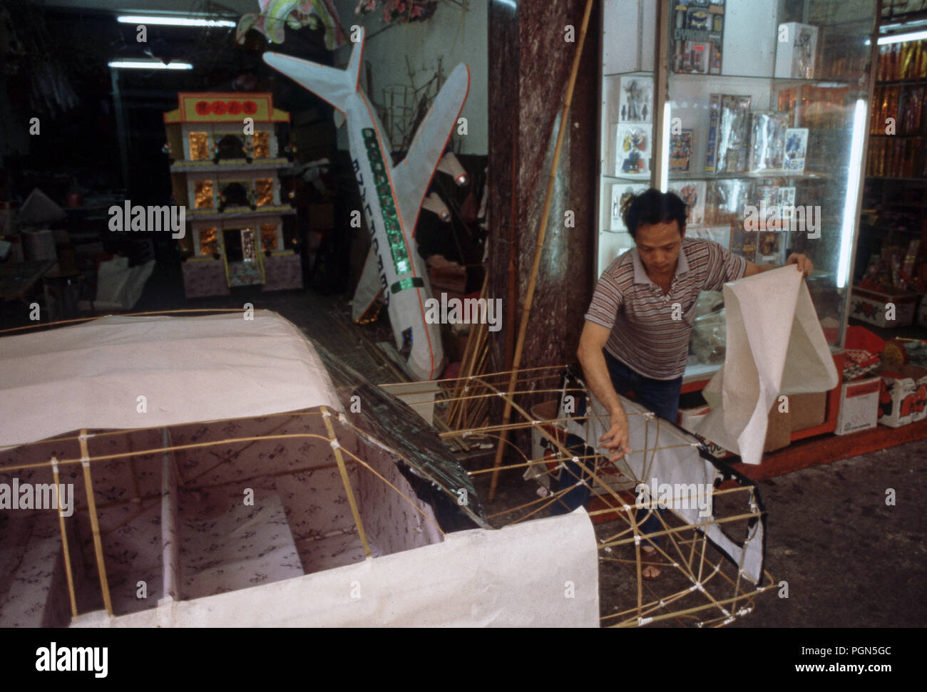 Hong Kong l uomo crea la carta effigi noto anche come Joss carta - Cinese tradizionale offerte che simboleggiano tutti i beni materiali uno potrebbe aver bisogno nell'aldilà - è bruciato per i loro antenati defunti. È derivata da un mix di Taoismo e Buddismo e folklore regionale. Foto Stock