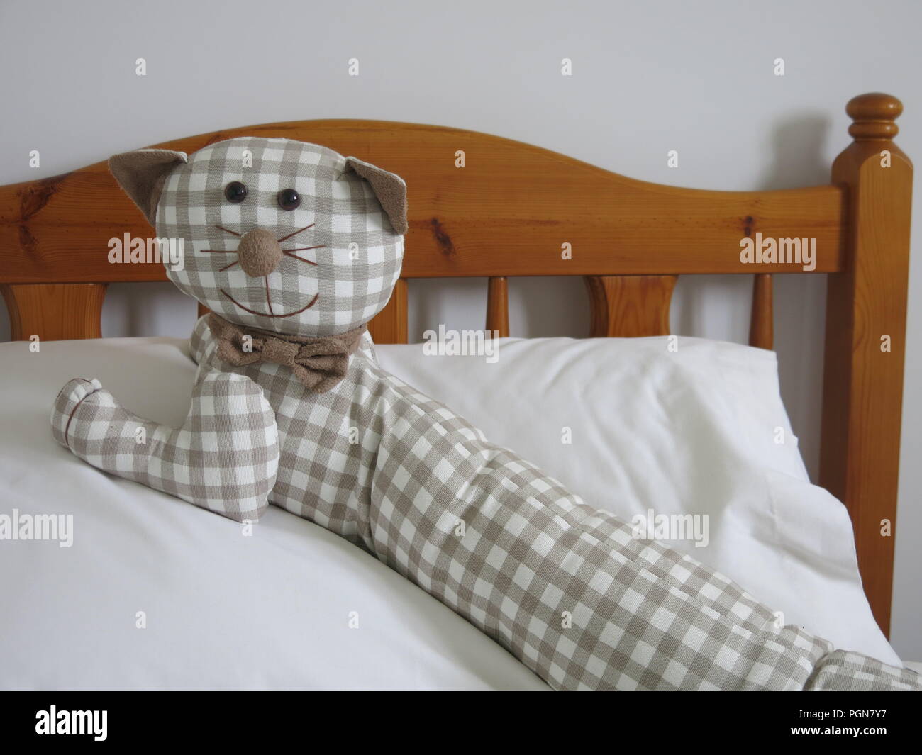 Questo giocattolo imbottito cat, fatta dal tessuto gingham, è reclinabile sul letto e sembra abbastanza a casa. Foto Stock