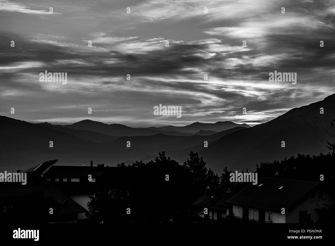 Profilo di montagna e città con cielo molto nuvoloso in bianco e nero Foto Stock