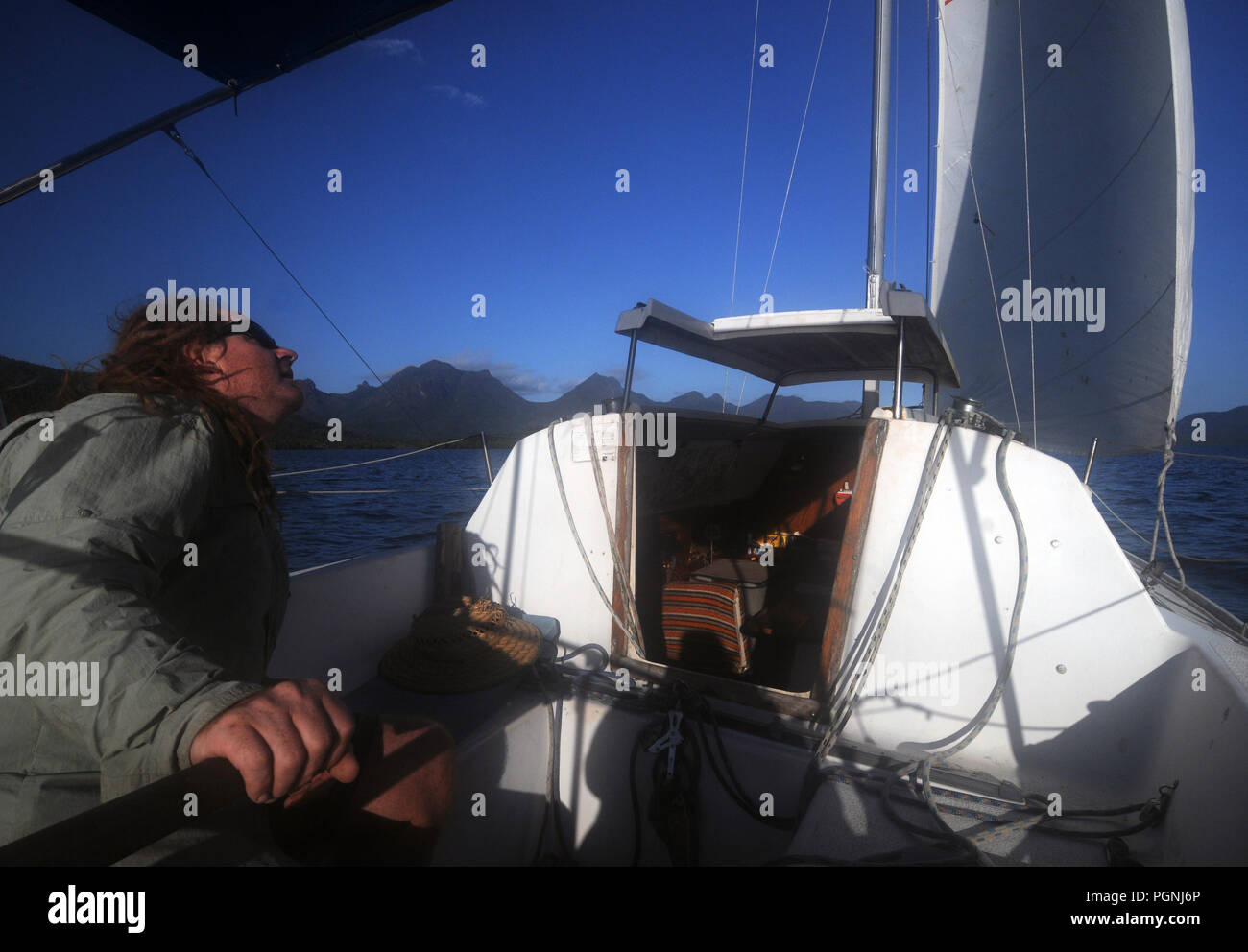 Sailor controllo vela sul piccolo yacht, Hinchinbrook Channel, Queensland, Australia. No signor o PR Foto Stock
