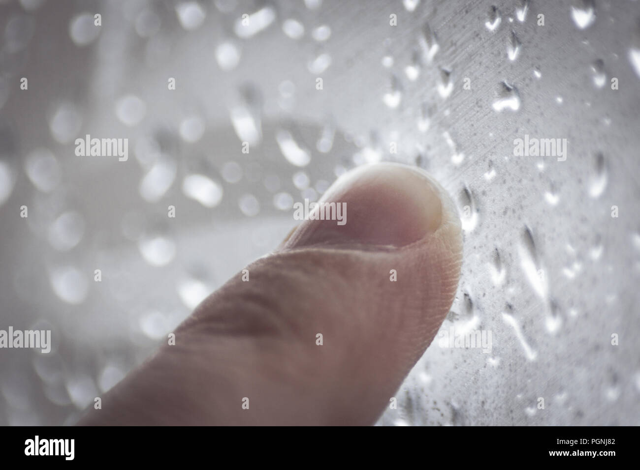 Moody sentimenti concetto: dito di un adolescente di disegno sulla finestra con le gocce di pioggia in un giorno di pioggia Foto Stock