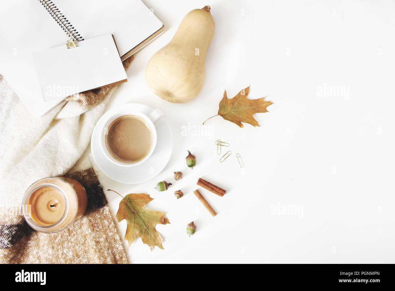 Caduta di stile femminile composizione. Area di lavoro in autunno ancora in vita. Notebook mock-up in scena con la tazza di caffè, coperta di lana, foglie di autunno e di zucca. Tavolo bianco sullo sfondo. Appartamento laico, vista dall'alto. Foto Stock