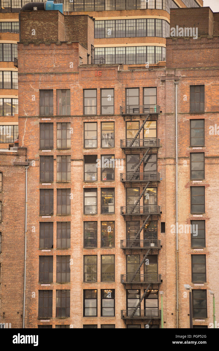 Vista della vecchia torreggiante edificio in mattoni di New York City che ospita appartamenti e mostra finestre e al di fuori delle uscite di sicurezza Foto Stock