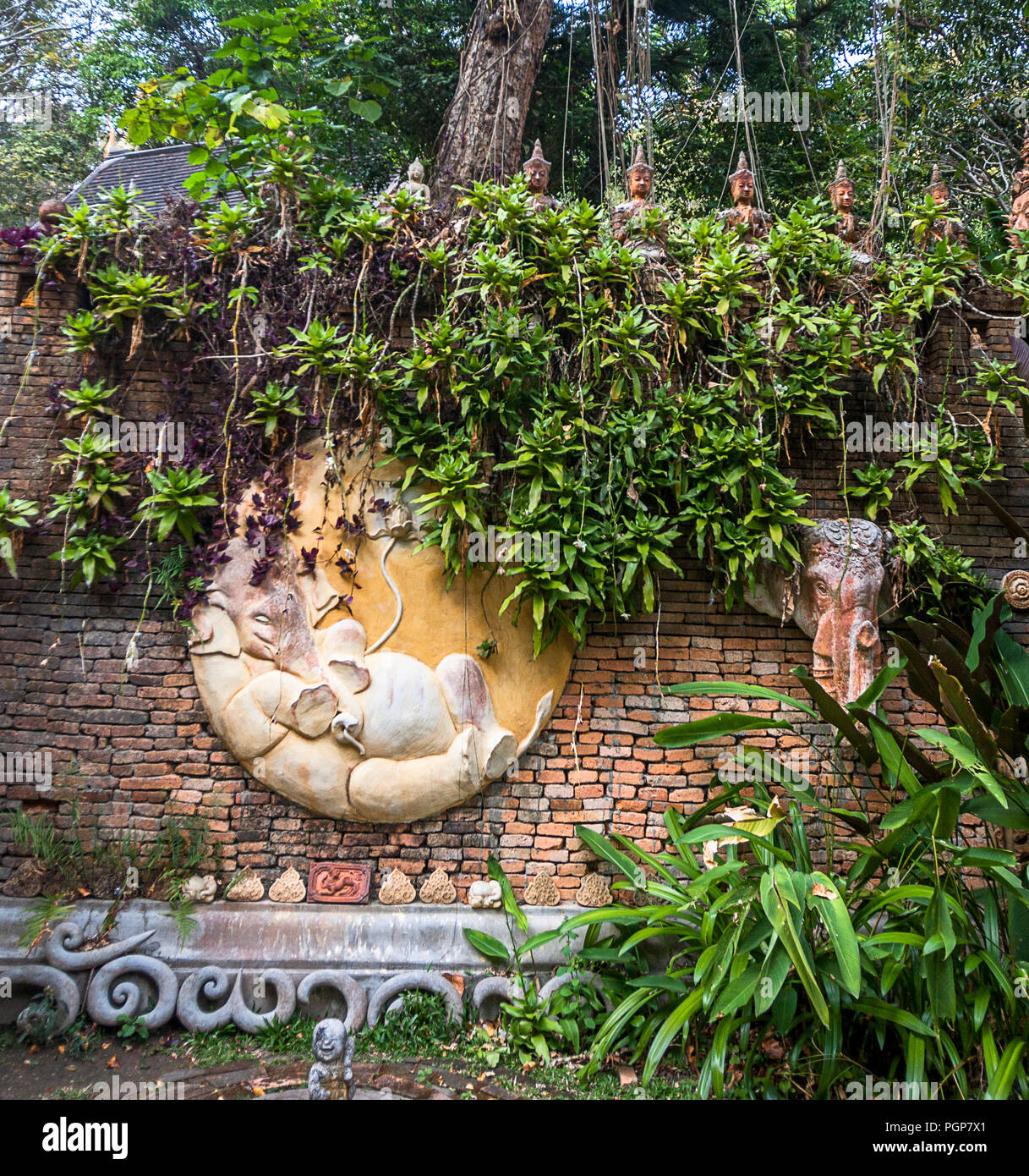 Elefante scolpito su un muro di mattoni al tempio buddista al di sopra di Chiang Mai. Più piccolo Buddha sono allineati al di sopra del elepant. Foto Stock