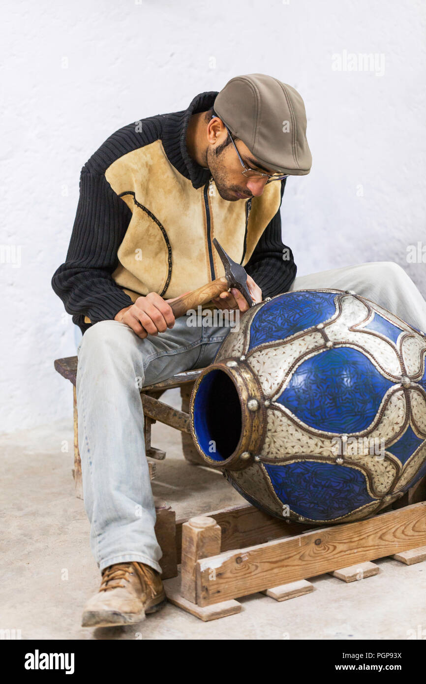 Il Marocco ceramica artista lavora su un grande vaso o urna con smalto blu e accenti di metallo. La posizione è Fes, che è un centro di terracotta fine produzione. Foto Stock