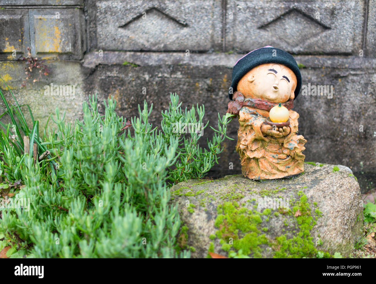 Una statua buddista tenendo un mikan orange sorge sul ciglio della strada appena fuori la Shimanami Kaido percorso in bicicletta su Oshima isola in città Imabari, Ehime Pre Foto Stock