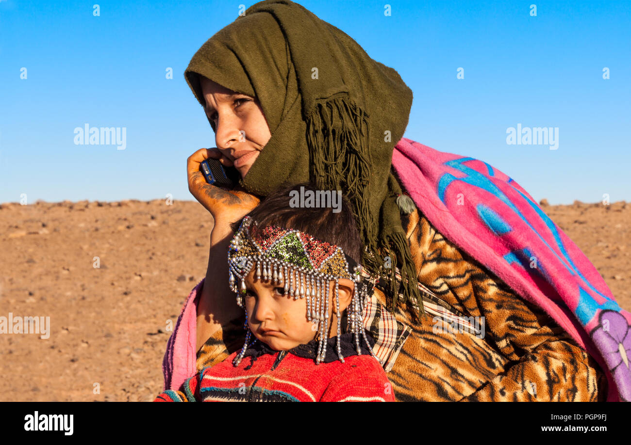 Bambini nomadi e madre su un telefono cellulare nella regione di Maider del deserto del Sahara in Marocco il 28 dicembre, 2012. Nomads pascolare il loro bestiame. Foto Stock