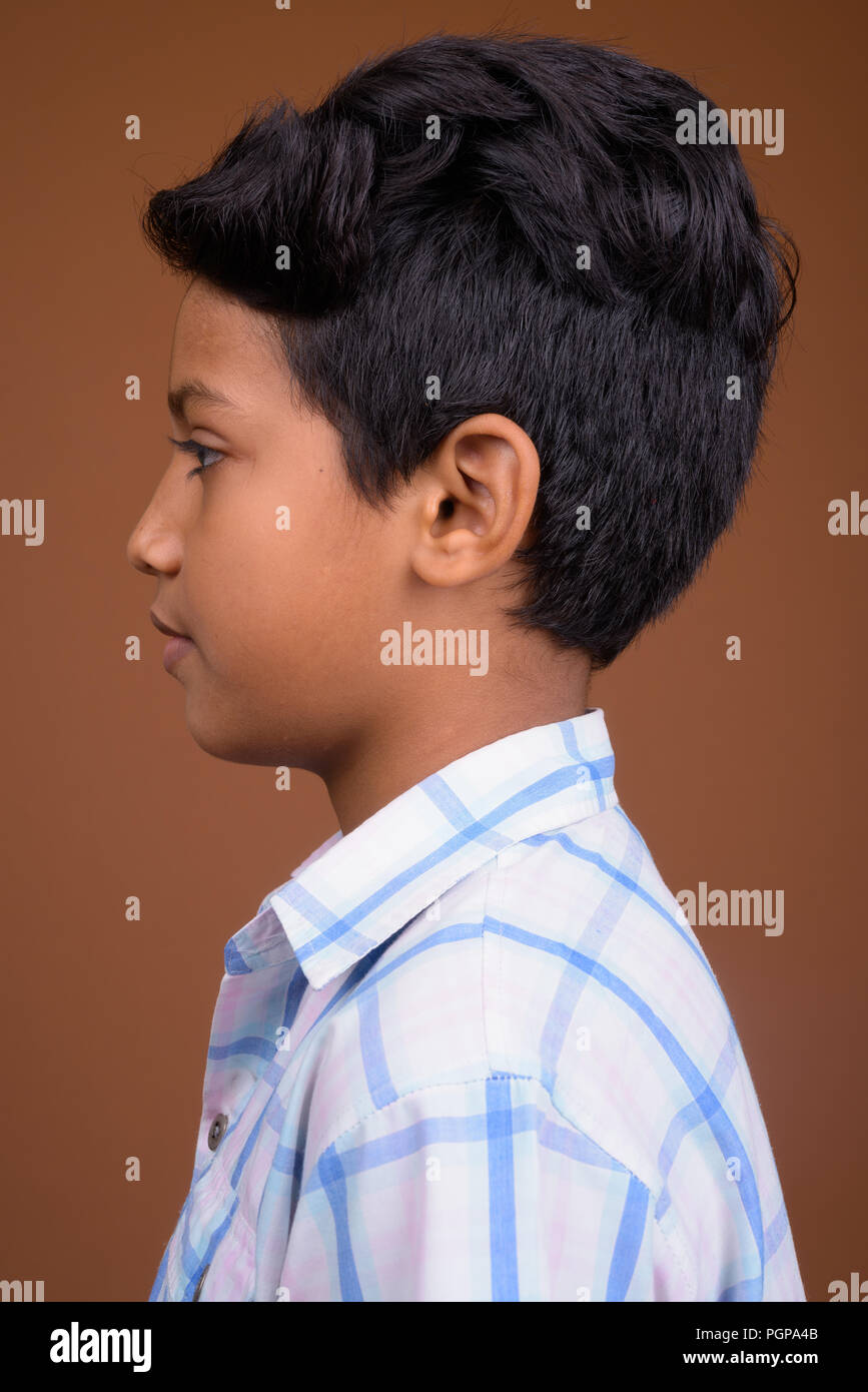 Giovane ragazzo indiano indossando camicia a scacchi contro backgroun marrone Foto Stock