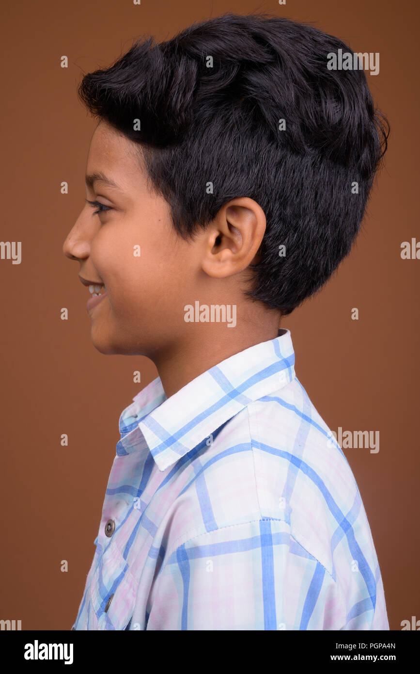 Giovane ragazzo indiano indossando camicia a scacchi contro backgroun marrone Foto Stock