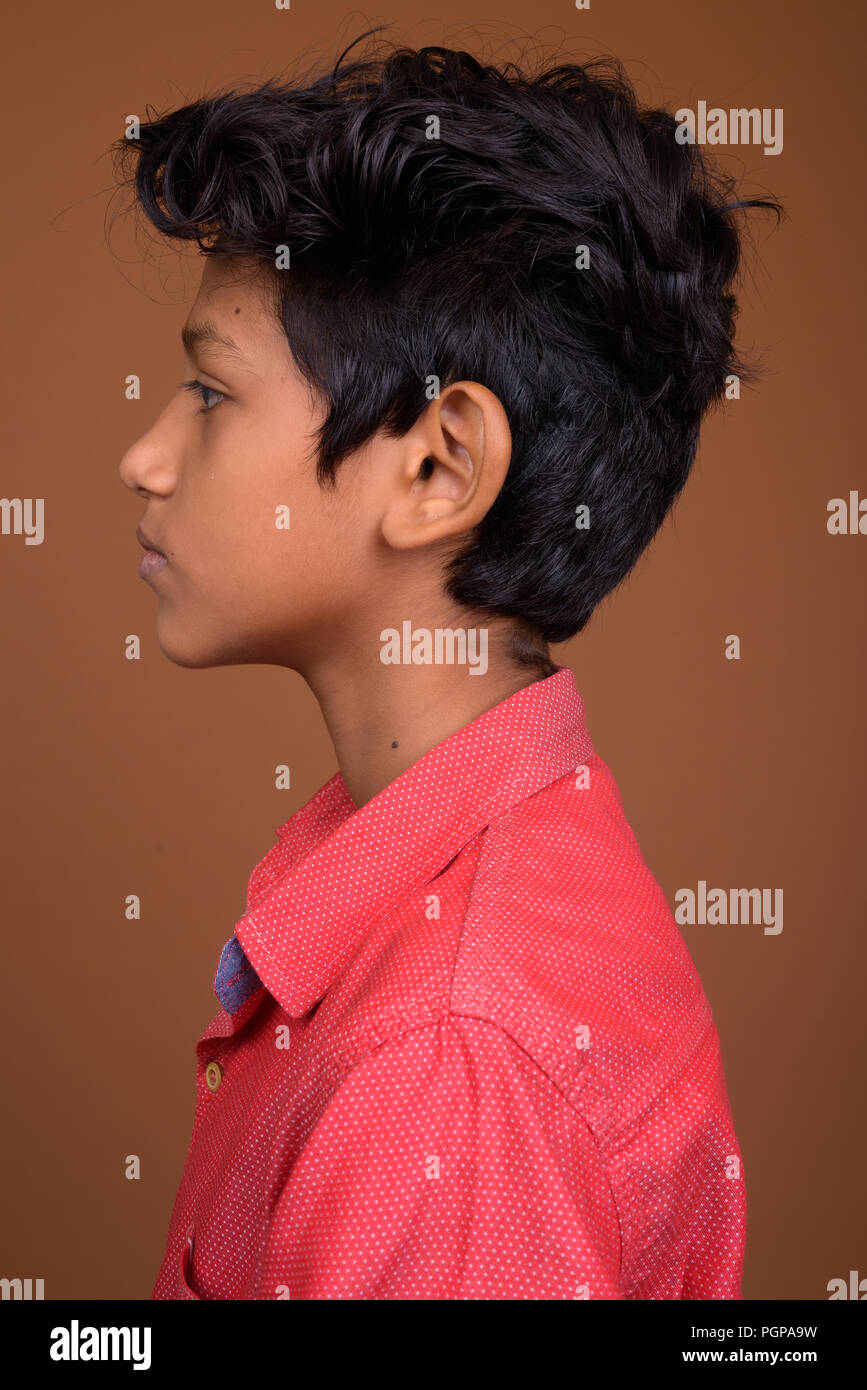 Giovane ragazzo indiano smart indossare abbigliamento casual contro brown bac Foto Stock
