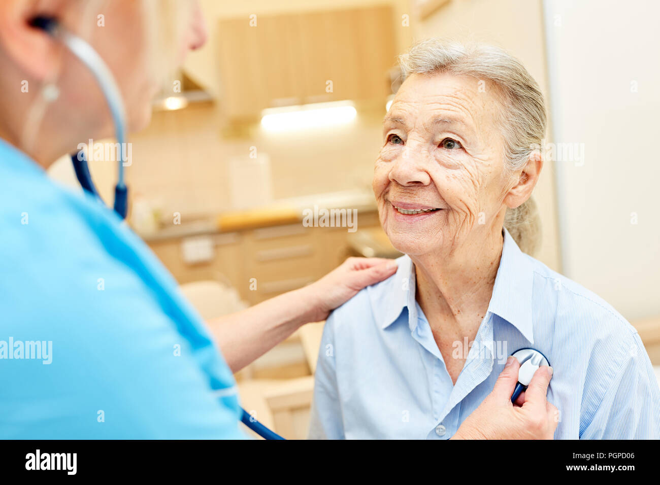 Un medico o un infermiere esamina una donna senior con lo stetoscopio Foto Stock