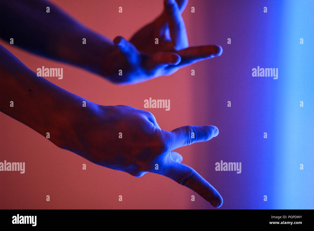 Le mani umane in colore rosso e blu neon luce fluorescente Foto Stock