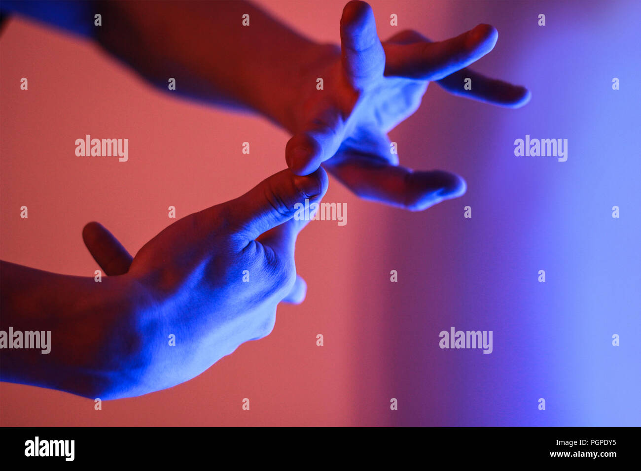 Le mani umane in colore rosso e blu neon luce fluorescente Foto Stock