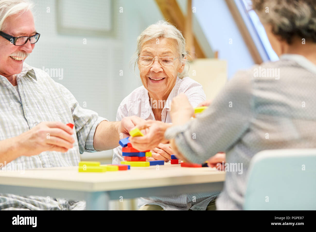 Gruppo di anziani con demenza si diverte a giocare con la costruzione di blocchi di occupazione Foto Stock