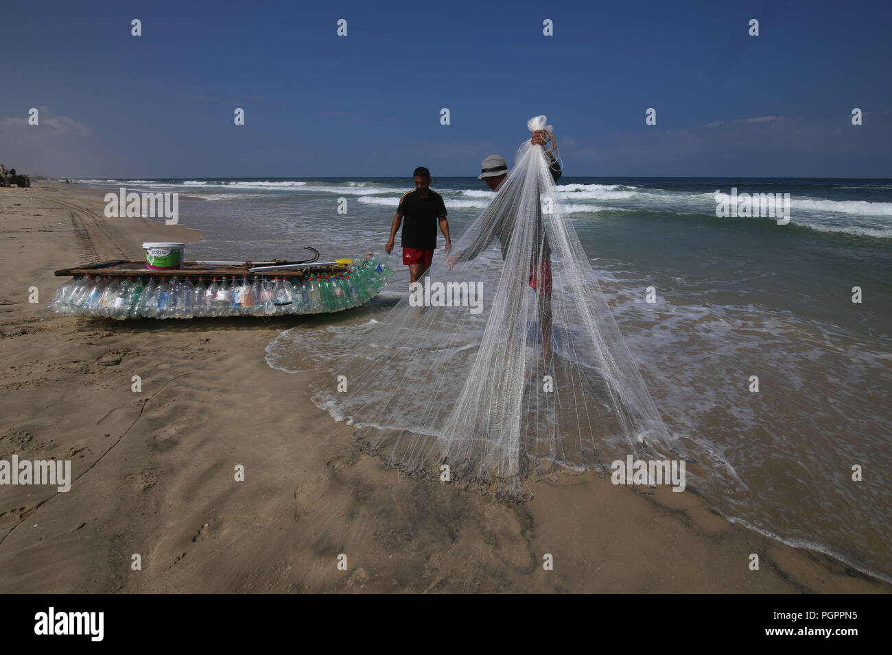 (180828) -- GAZA, Agosto 28, 2018 (Xinhua) -- pescatore palestinese Mouath Abu Zeid (L) e il suo amico il lavoro sulla barca di plastica su una spiaggia a sud di Gaza città di Rafah, che il 28 agosto, 2018. Zeid utilizzato 700 bottiglie vuote e la filettatura danneggiata dalle reti da pesca per rendere la sua barca a vela non troppo lontano ma abbastanza lontano per la cattura di circa da tre a cinque chili di pesce al giorno. -Israeliano bloccato nella Striscia di Gaza la crescente disoccupazione prompt problemi palestinesi per trovare nuove opportunità di lavoro. (Xinhua/Khaled Omar) (lrz) Foto Stock