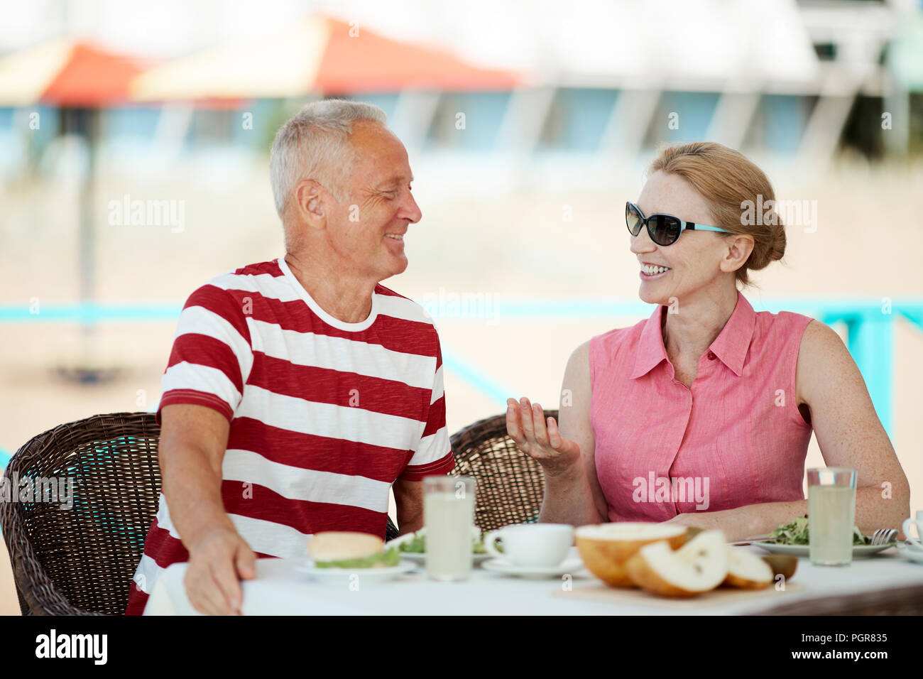 Allegro coniugi maturi per discutere le loro impressioni da vacanza al resort estivo da prima colazione Foto Stock