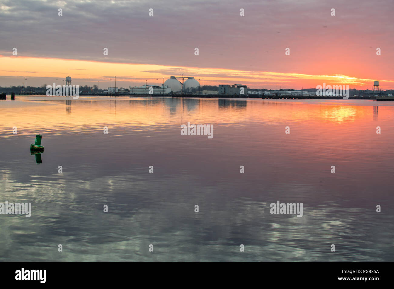Fiume calmo lungo un industriale waterside al tramonto Foto Stock