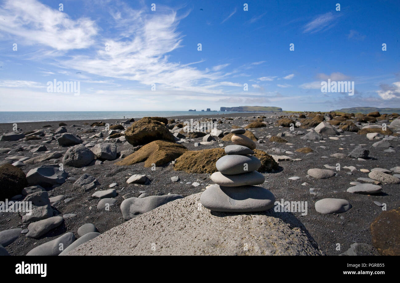 Una spiaggia di sabbia nera a Dyrholaey riserva vicino Vik Islanda. Il Cairn segna l'area come elf habitat. Foto Stock