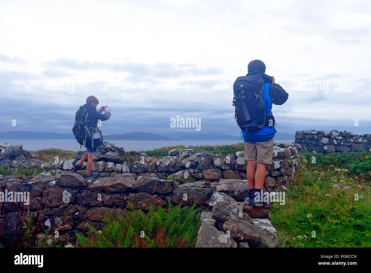 I ragazzi in piedi sulle rovine e scattare foto del villaggio abbandonato nel 1857 sulla lunga, Treshnish Isole Ebridi Interne, Scozia Foto Stock