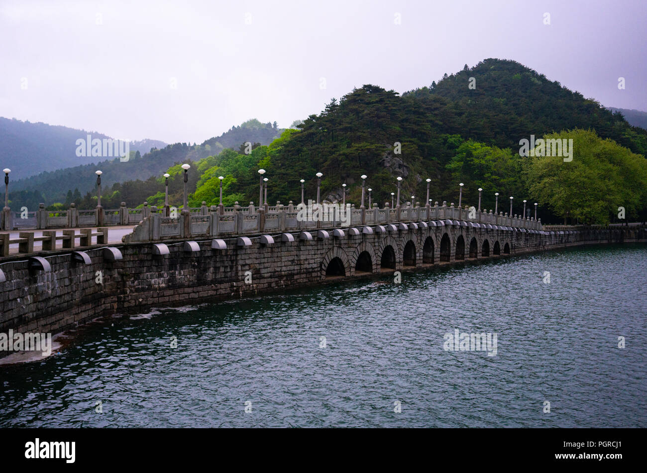 Ponte cinese su una diga con Lulin lago e montagne verdi vista nel Parco nazionale di Lushan nello Jiangxi Cina Foto Stock