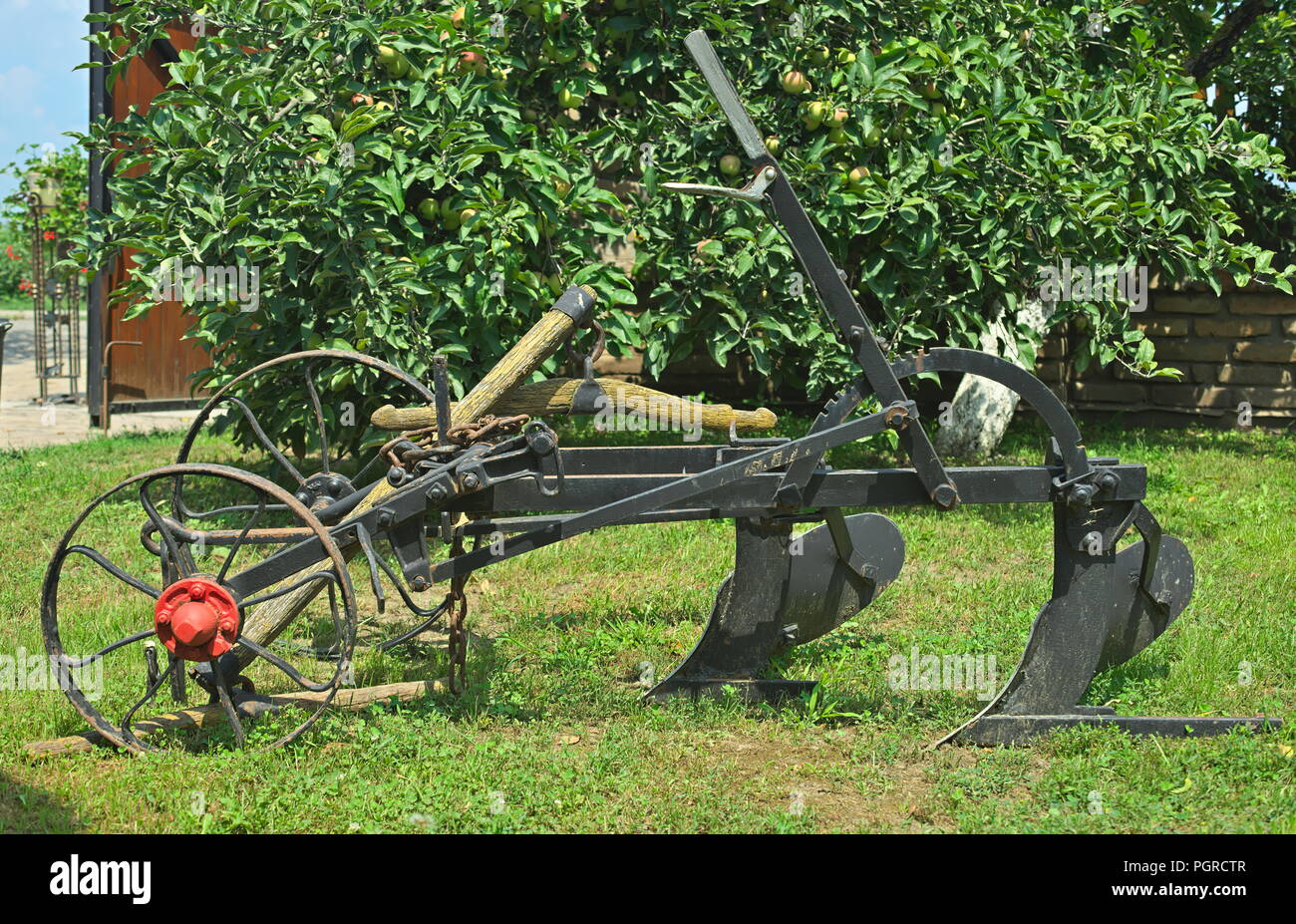 Vecchio vintage restaurati seduta dell'aratro sull'erba in cantiere Foto Stock