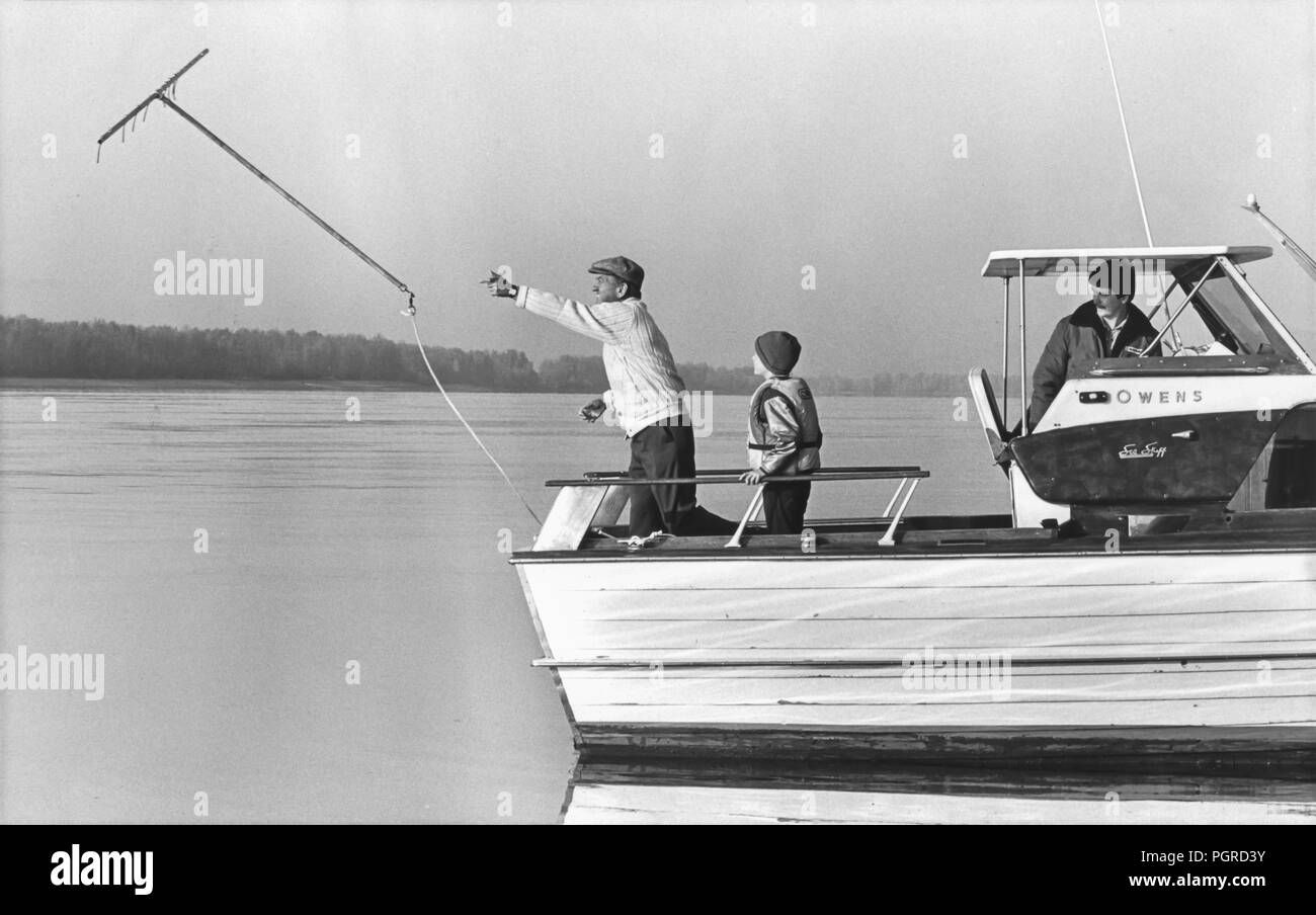 VANCOUVER, WASHINGTON, STATI UNITI D'America - 24 novembre 1982: ricerca Columbia River per D. B. Cooper rimane e denaro. Richard Tosaw lancia lo strumento di dragaggio off barca. Il 9 novembre 24, 1971, Cooper dirottato Northwest Airlines jet nel vicino a Portland, Oregon e paracadutato fuori con 200.000 dollari in contanti ha estorto dalla compagnia aerea. Brian Ingram (al centro), il 11-anno-vecchio ragazzo che ha trovato $5.800 segnati di banconote da 20 € in febbraio1980, guarda a. Foto Stock