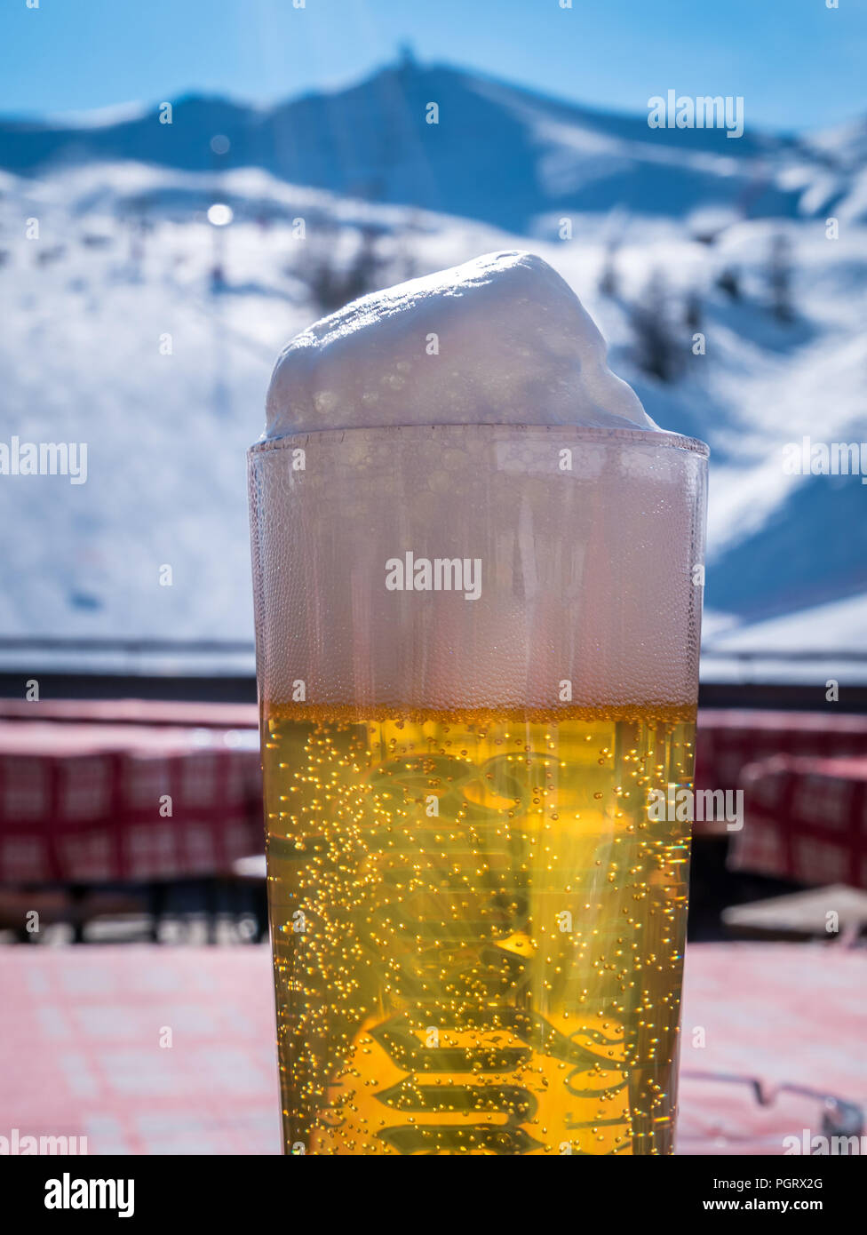 Close-up di schiuma della birra. Progetto di birra in vetro con paesaggio invernale in background. Piste da sci nelle giornate di sole. Foto Stock