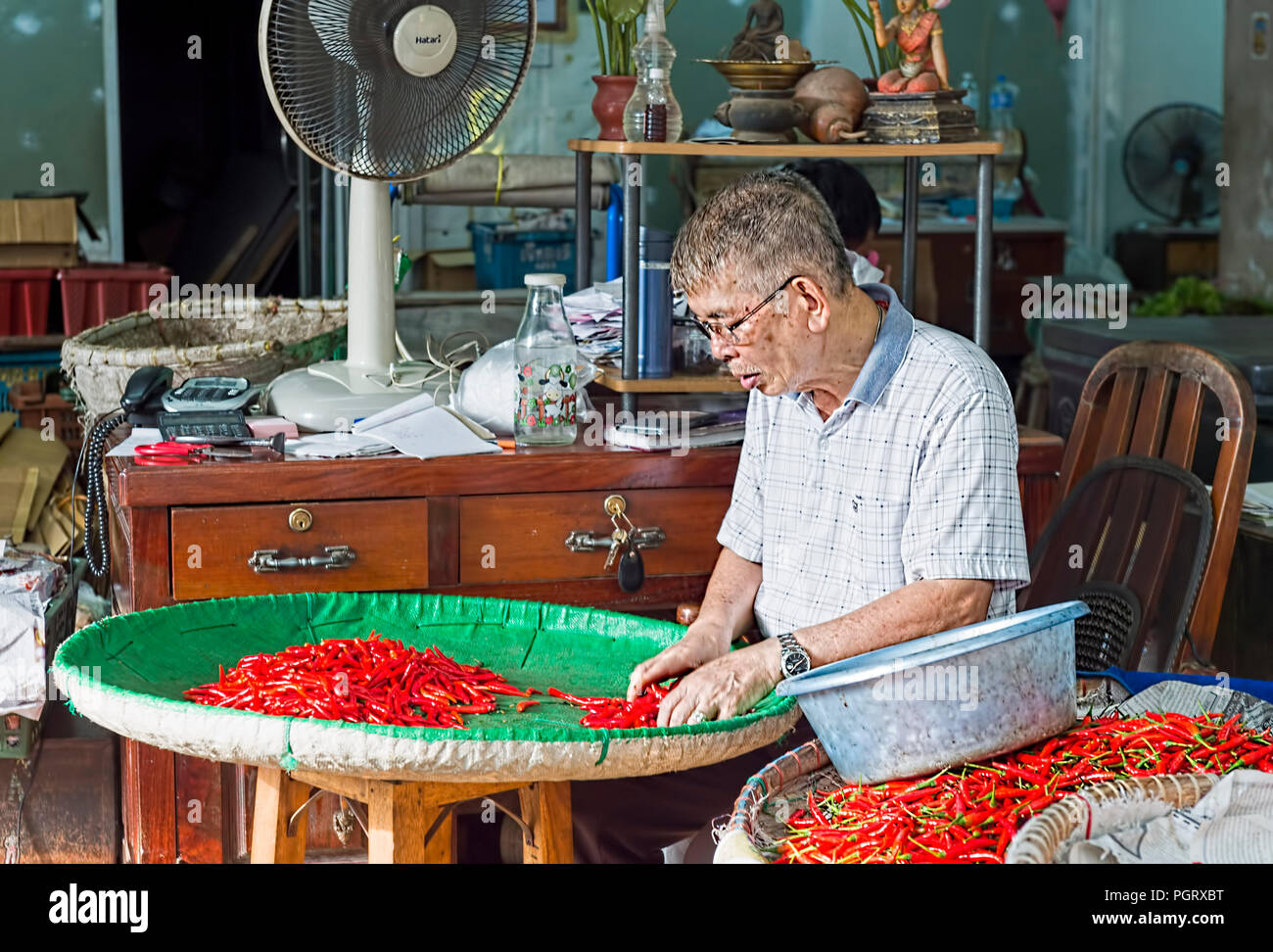 Pak Khlong Talat Market Bangkok - anziano gentiluomo ordinamento di peperoncino rosso in un cestello di verde Foto Stock