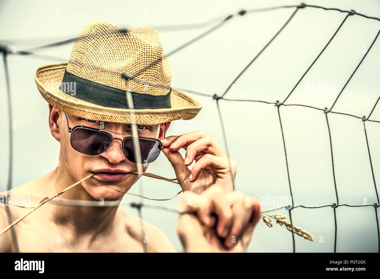 Giovane uomo che indossa cappello di paglia in piedi nei campi Foto Stock